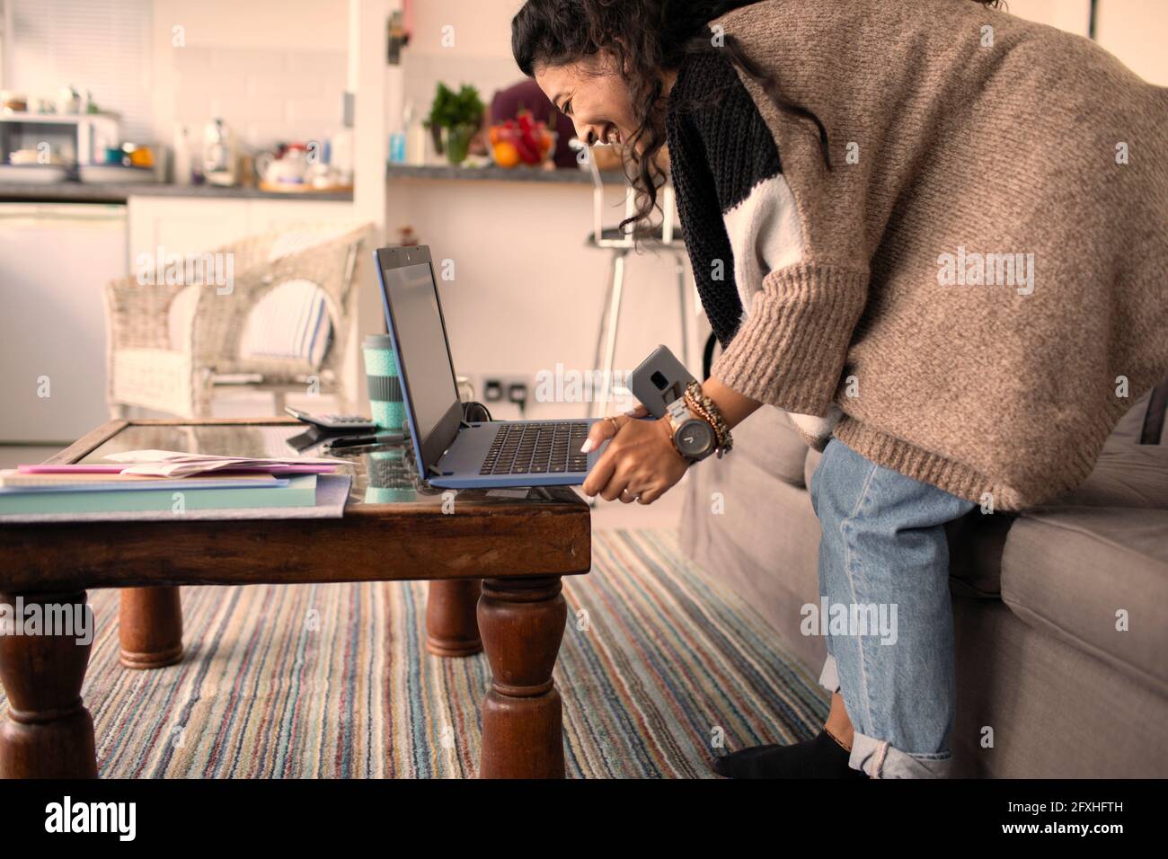 Glückliche Frau, die von zu Hause aus am Laptop im Wohnzimmer arbeitet Stockfoto