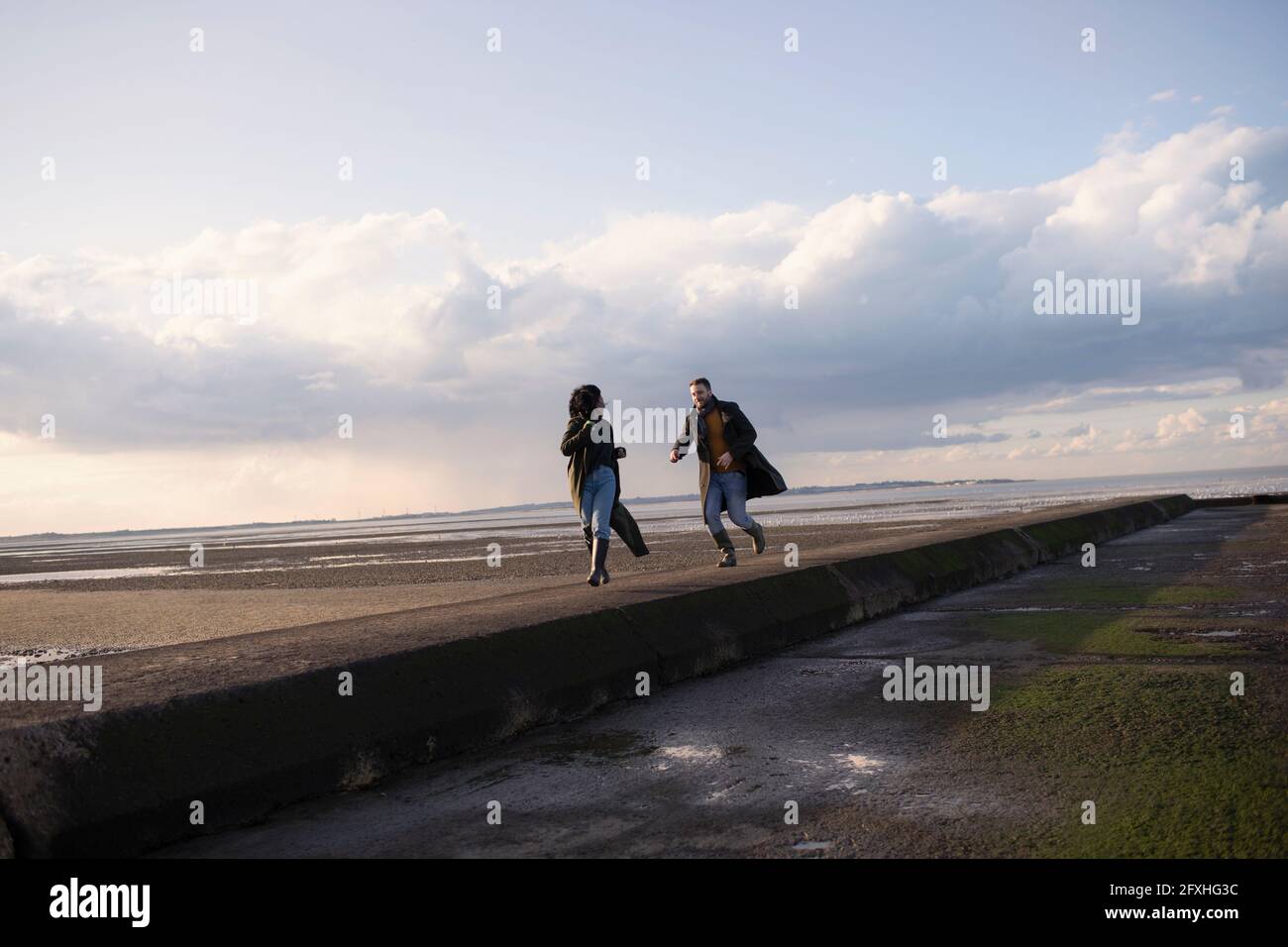Pärchen, die auf dem Meeresstrand-Steg laufen Stockfoto