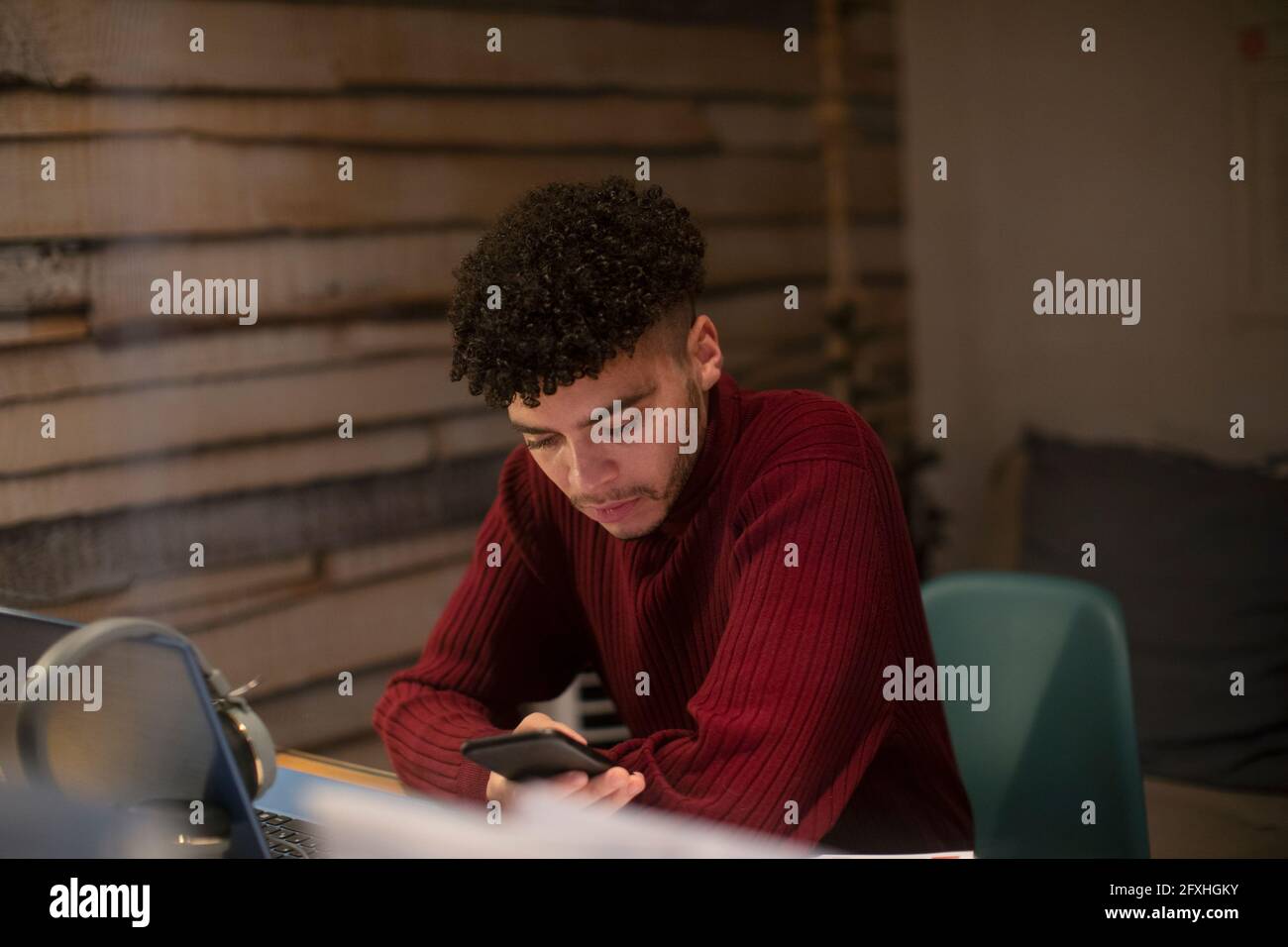 Fokussierter junger Mann mit Smartphone, der im Heimbüro arbeitet Stockfoto