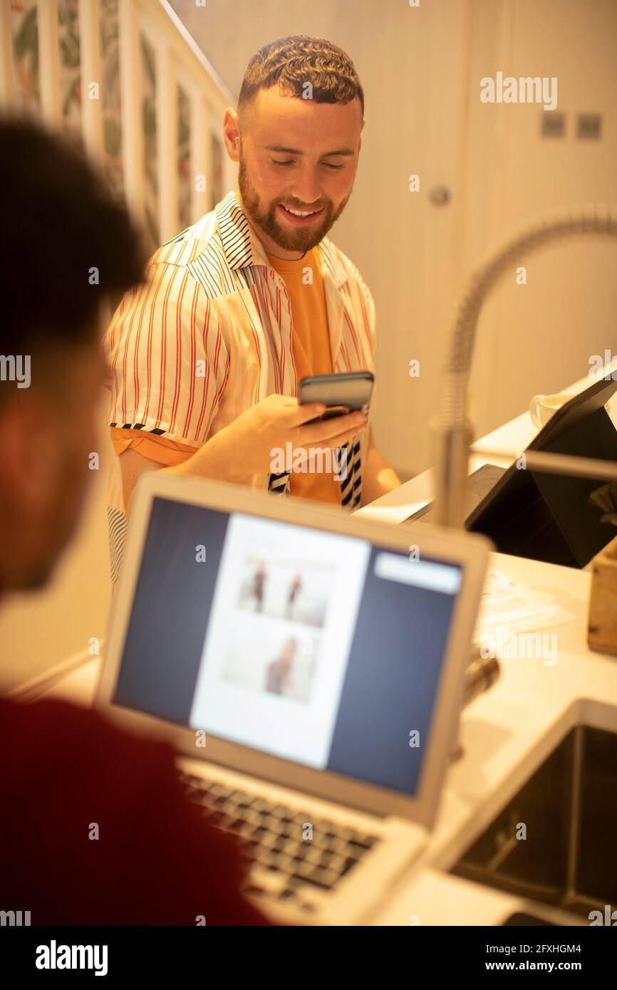 Junge schwule Paar arbeitet von zu Hause aus und mit Smartphone Stockfoto