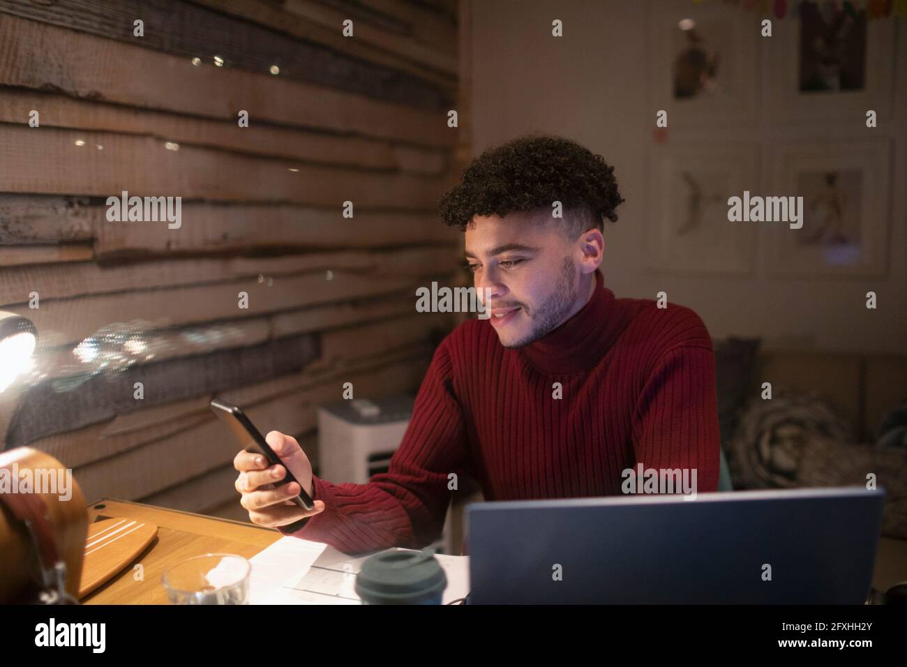 Junger Mann mit Smartphone, der von zu Hause im Büro arbeitet Stockfoto