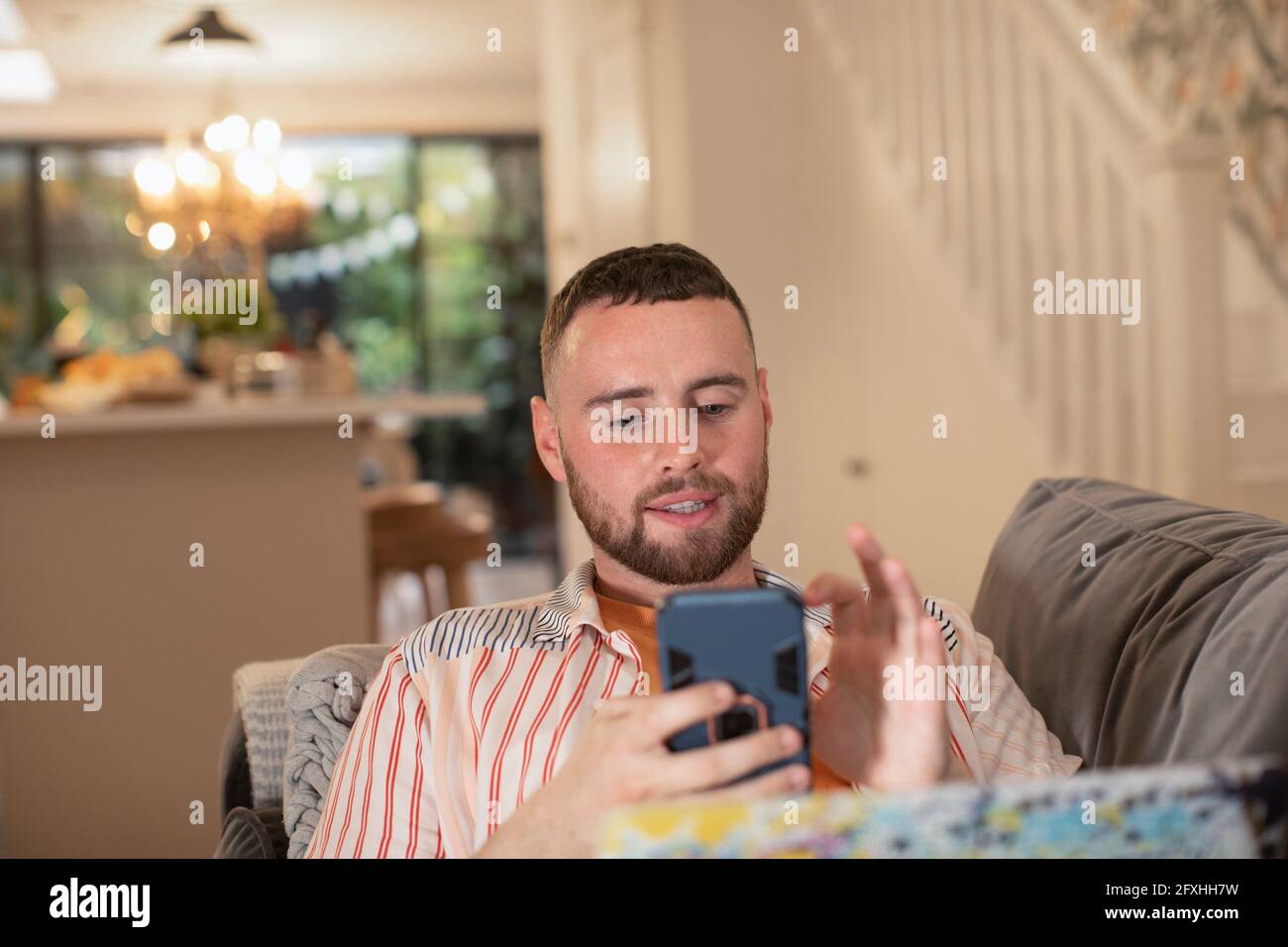 Junger Mann mit Smartphone auf dem Sofa Stockfoto