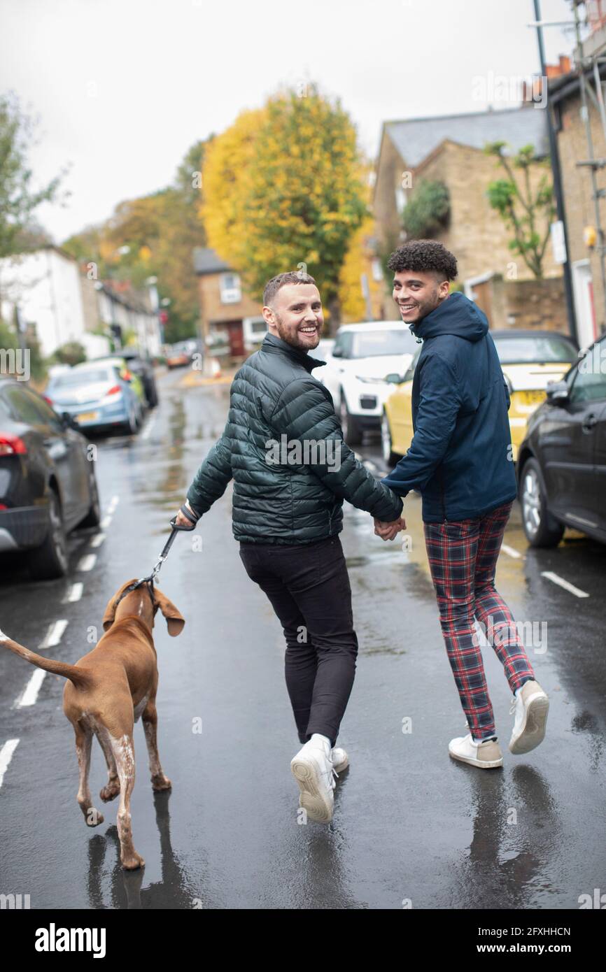 Portrait glücklich schwul männlichen Paar Hund auf nassen Herbst Straße gehen Stockfoto