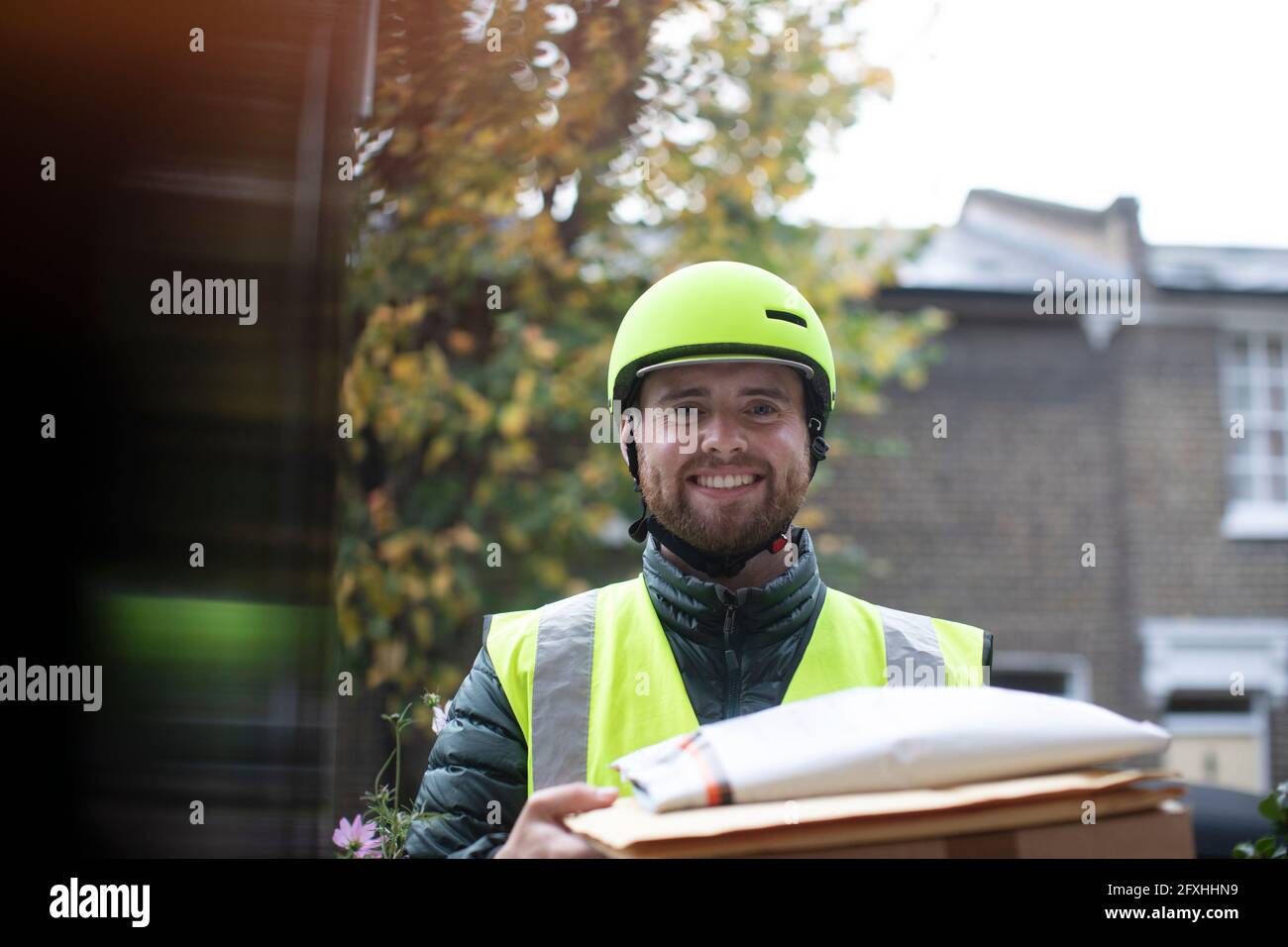 Portrait freundliche Lieferung Mann in Helm Pakete an die Tür liefern Stockfoto