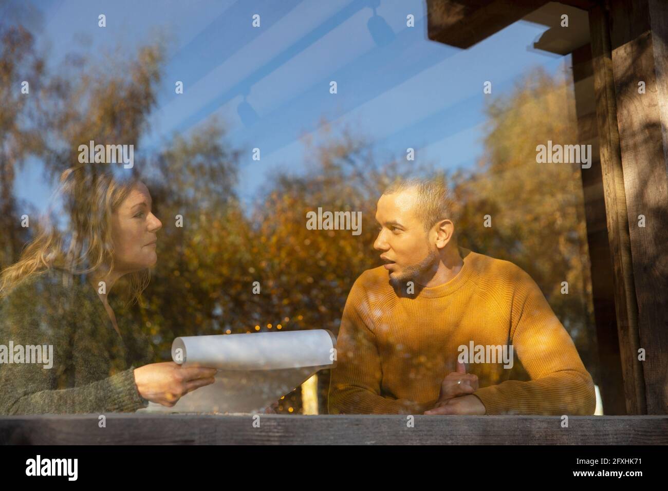 Geschäftsleute, die am sonnigen Cafe-Fenster über Papierkram diskutieren Stockfoto
