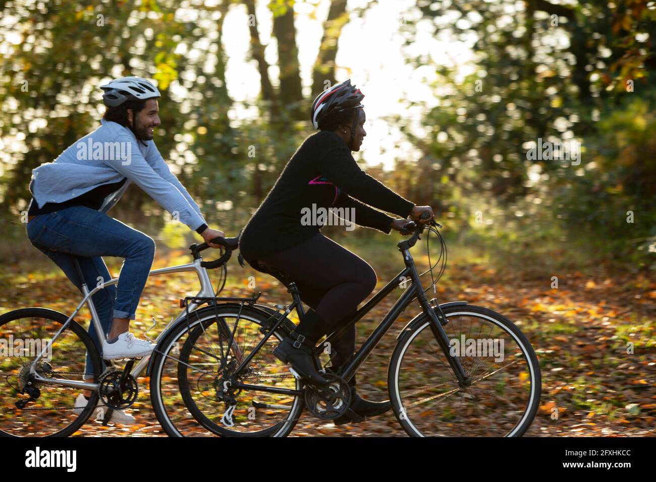 Freunde, die mit dem Fahrrad durch die Herbstblätter im Park fahren Stockfoto
