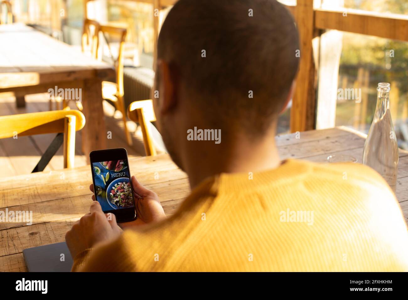 Männlicher Geschäftsinhaber, der auf dem Smartphone die Speisekarte des Restaurants ansieht Stockfoto