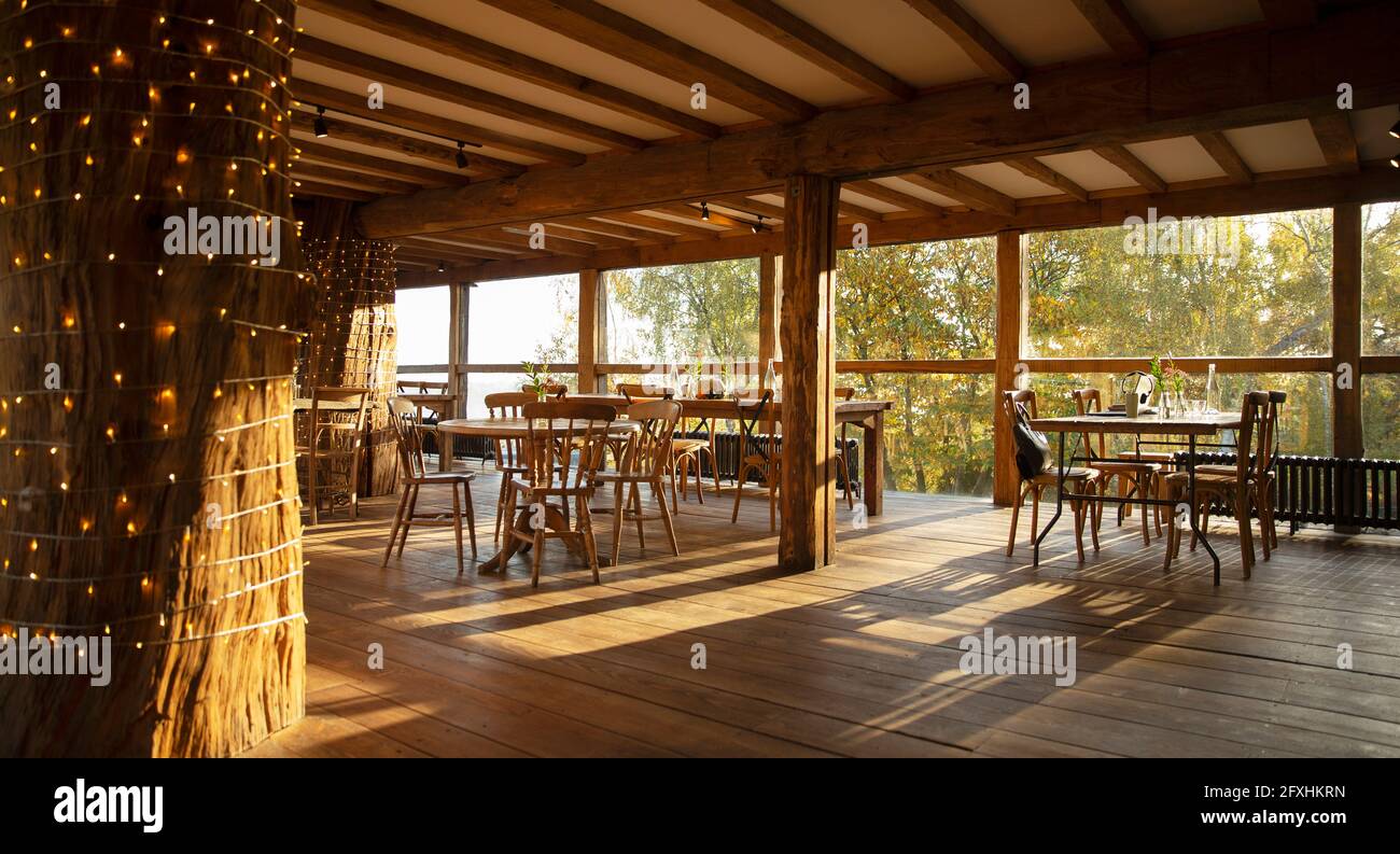 Holztische und -Stühle in einem sonnigen, leeren Restaurant Stockfoto