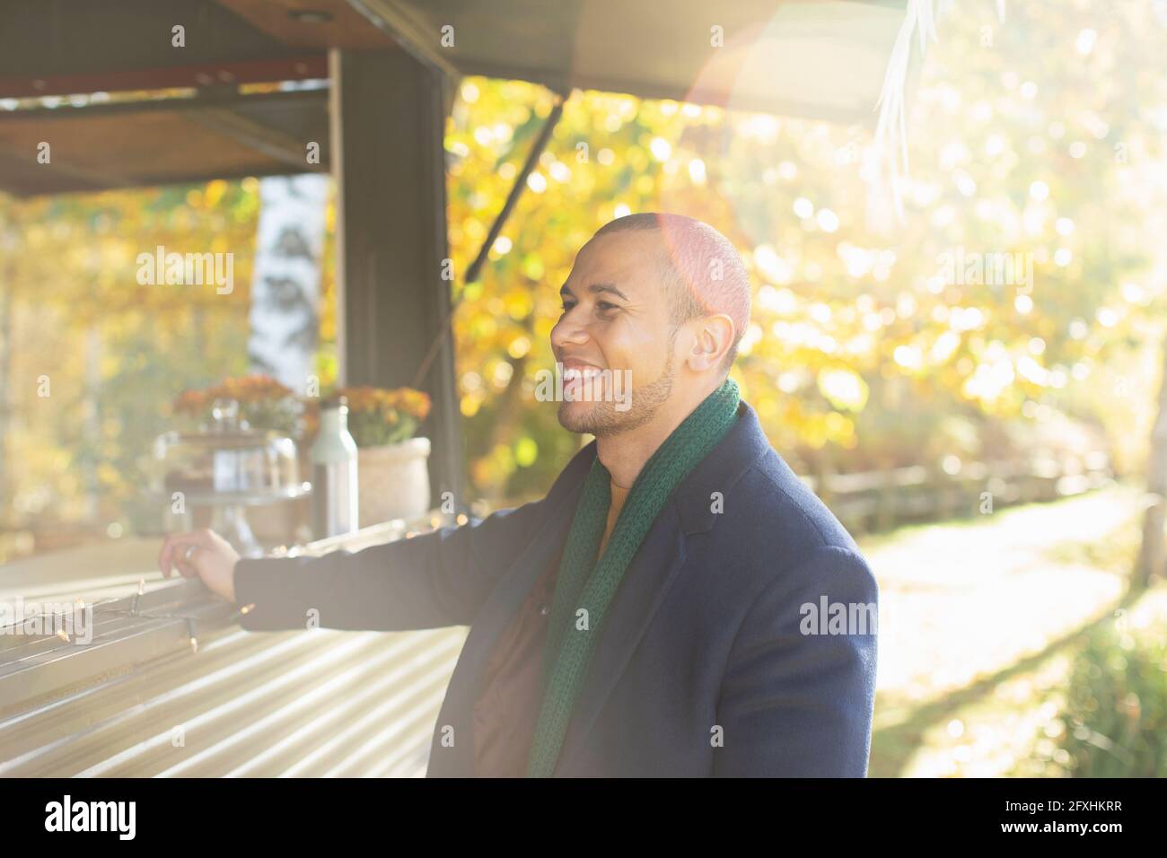 Glücklicher männlicher Kunde, der Lebensmittel im Food Cart im sonnigen Herbstpark bestellt Stockfoto