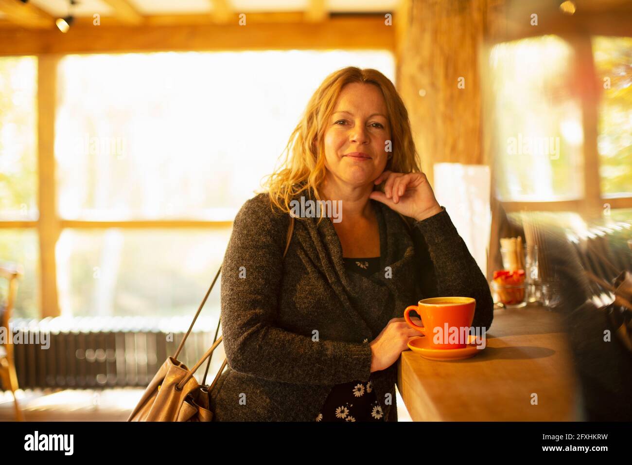 Portrait glückliche Frau, die Cappuccino am Cafe-Schalter bestellt Stockfoto