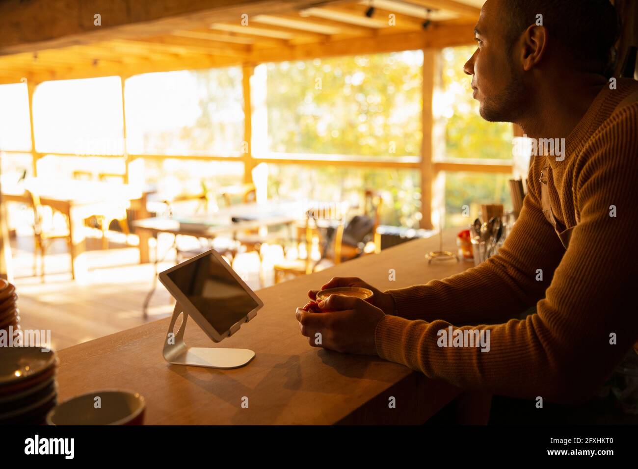 Nachdenklicher männlicher Cafe-Besitzer hinter dem Tresen Stockfoto