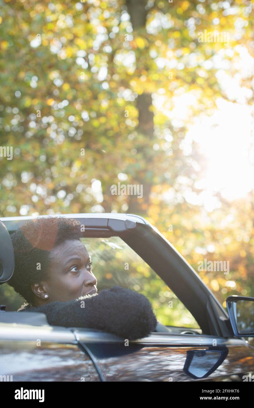 Frau, die im Cabrio im sonnigen Herbstpark reitet Stockfoto