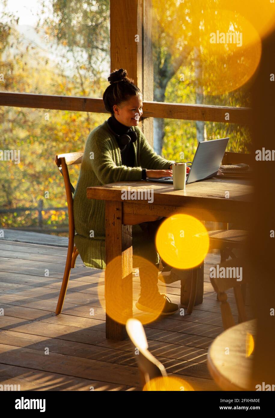Inhaber eines kleinen Unternehmens, der in einem sonnigen Herbstcafé am Laptop arbeitet Stockfoto