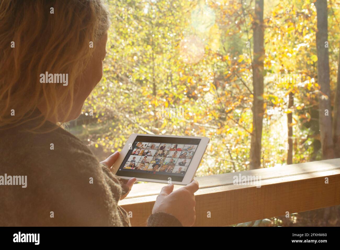 Frau chattet mit Freunden auf einem digitalen Tablet im Herbstfenster Stockfoto