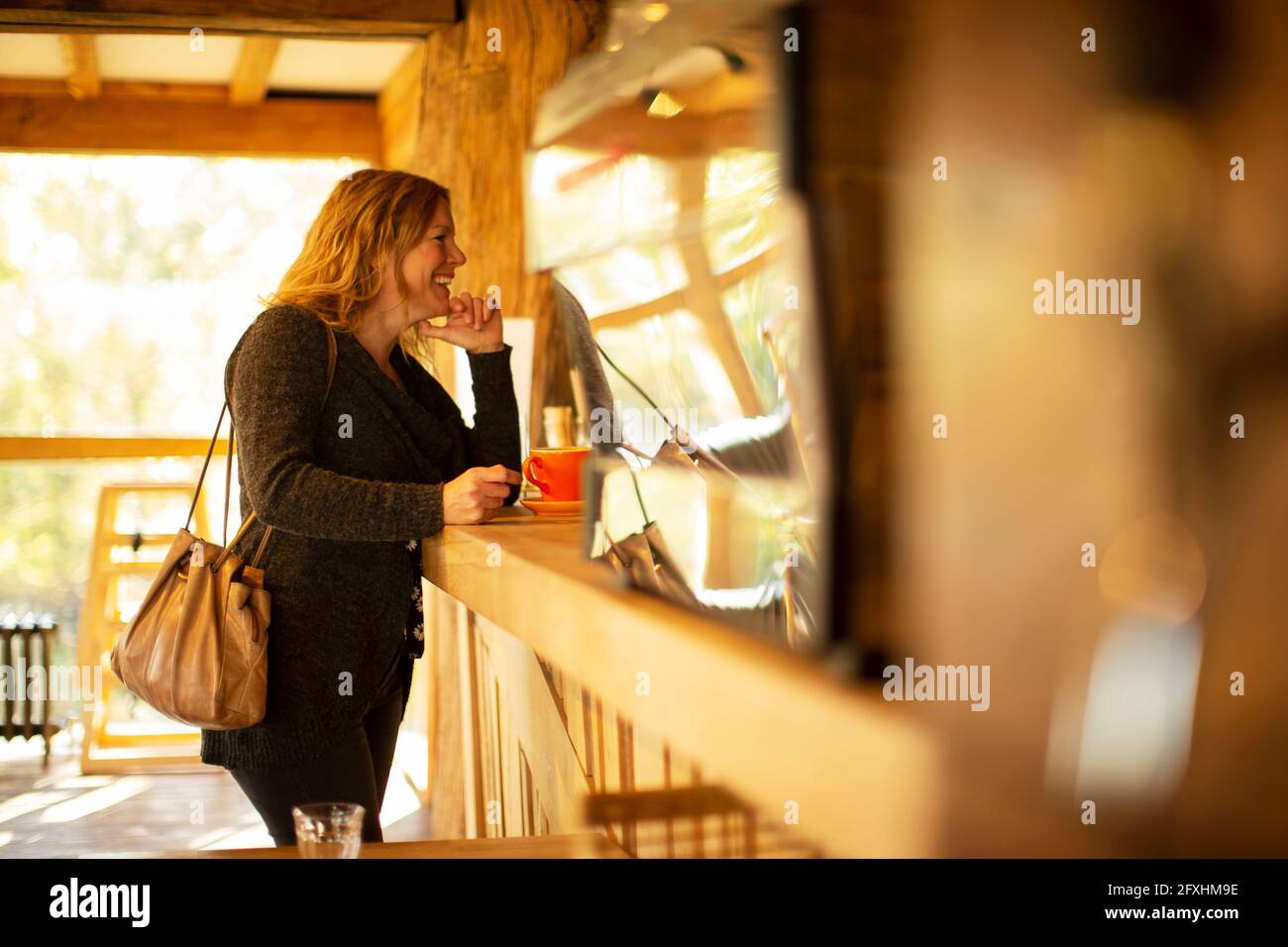 Glückliche weibliche Kundin, die Kaffee am Cafe-Schalter bestellte Stockfoto