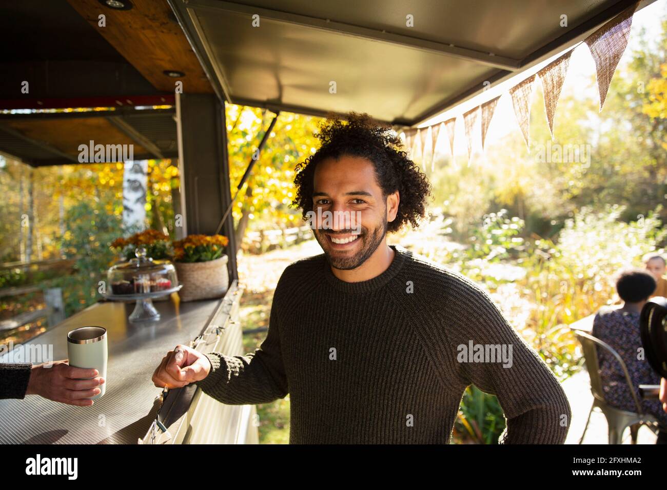 Portrait glücklicher männlicher Kunde, der Kaffee im Lebensmittelwagen im Park bestellt Stockfoto