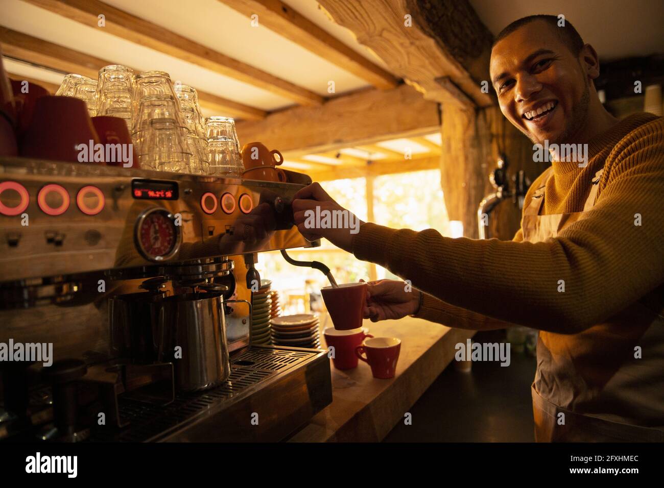 Portrait glücklicher Barista, der Kaffee an der Kaffeevollautomat zubereitet Stockfoto