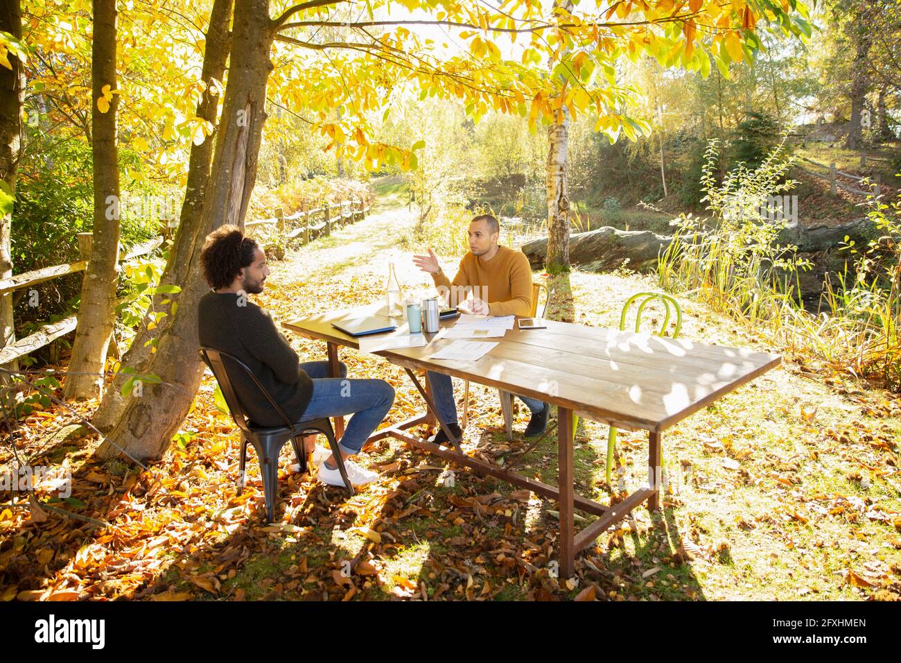 Geschäftsleute treffen sich am Tisch im sonnigen idyllischen Herbstpark Stockfoto