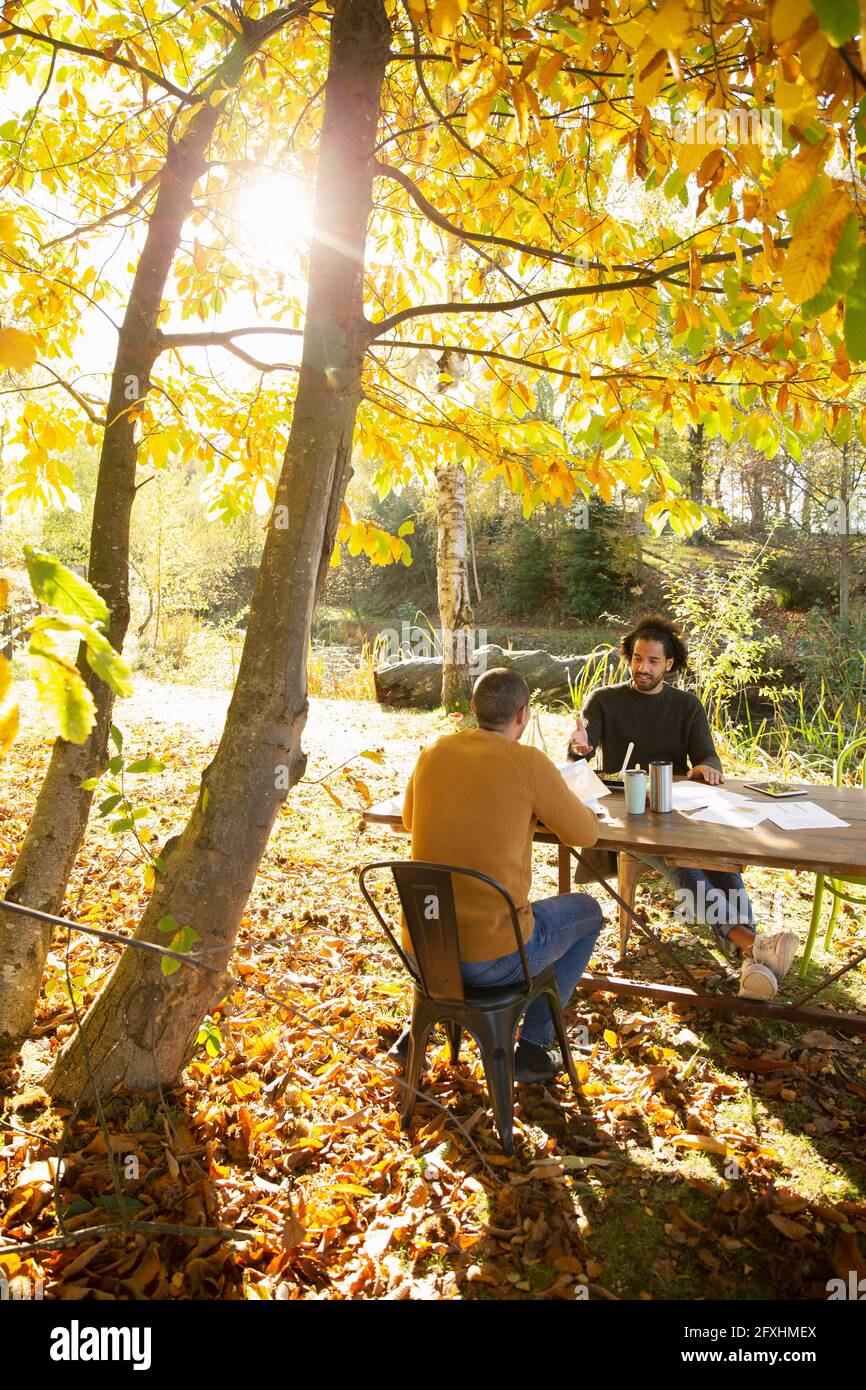 Geschäftsleute treffen sich am Tisch im sonnigen Herbstpark Stockfoto