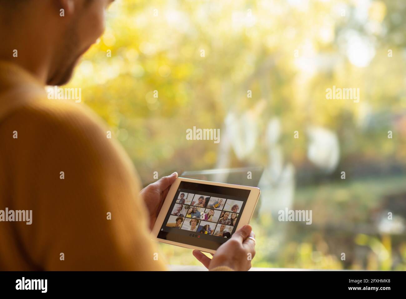Mann Video chatten mit Freunden auf dem digitalen Tablet-Bildschirm am Fenster Stockfoto