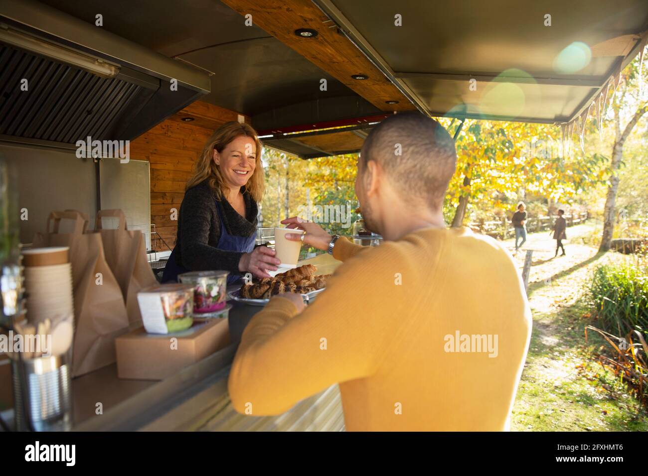 Freundlicher Besitzer des Food Cart, der den Gästen im Herbstpark Kaffee serviert Stockfoto