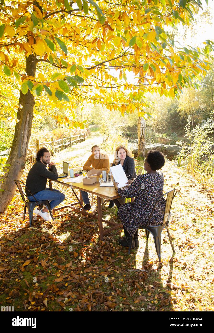Geschäftsleute mit Papierkram treffen sich am Tisch im sonnigen Herbstpark Stockfoto