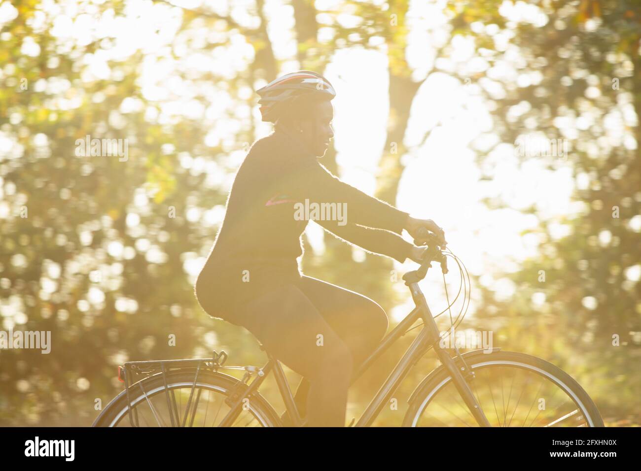 Frau im Helm Fahrrad fahren im sonnigen Herbstpark Stockfoto
