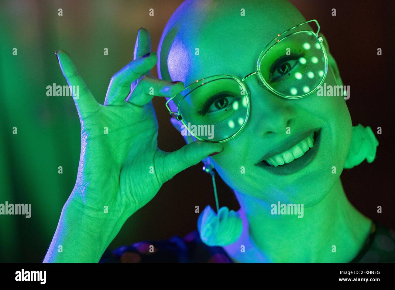 Nahaufnahme Porträt glückliche Frau mit Retro-Brille in grünem Licht Stockfoto