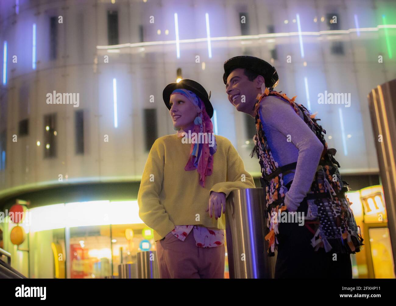 Ein modisches Paar unter dem neonfarbenen Stadtgebäude in der Nacht Stockfoto