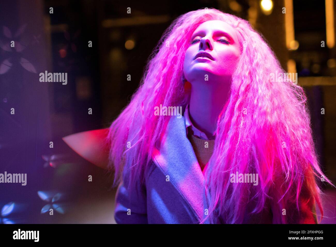 Schöne Frau mit rosa Haaren und Kopf zurück unter Licht Stockfoto