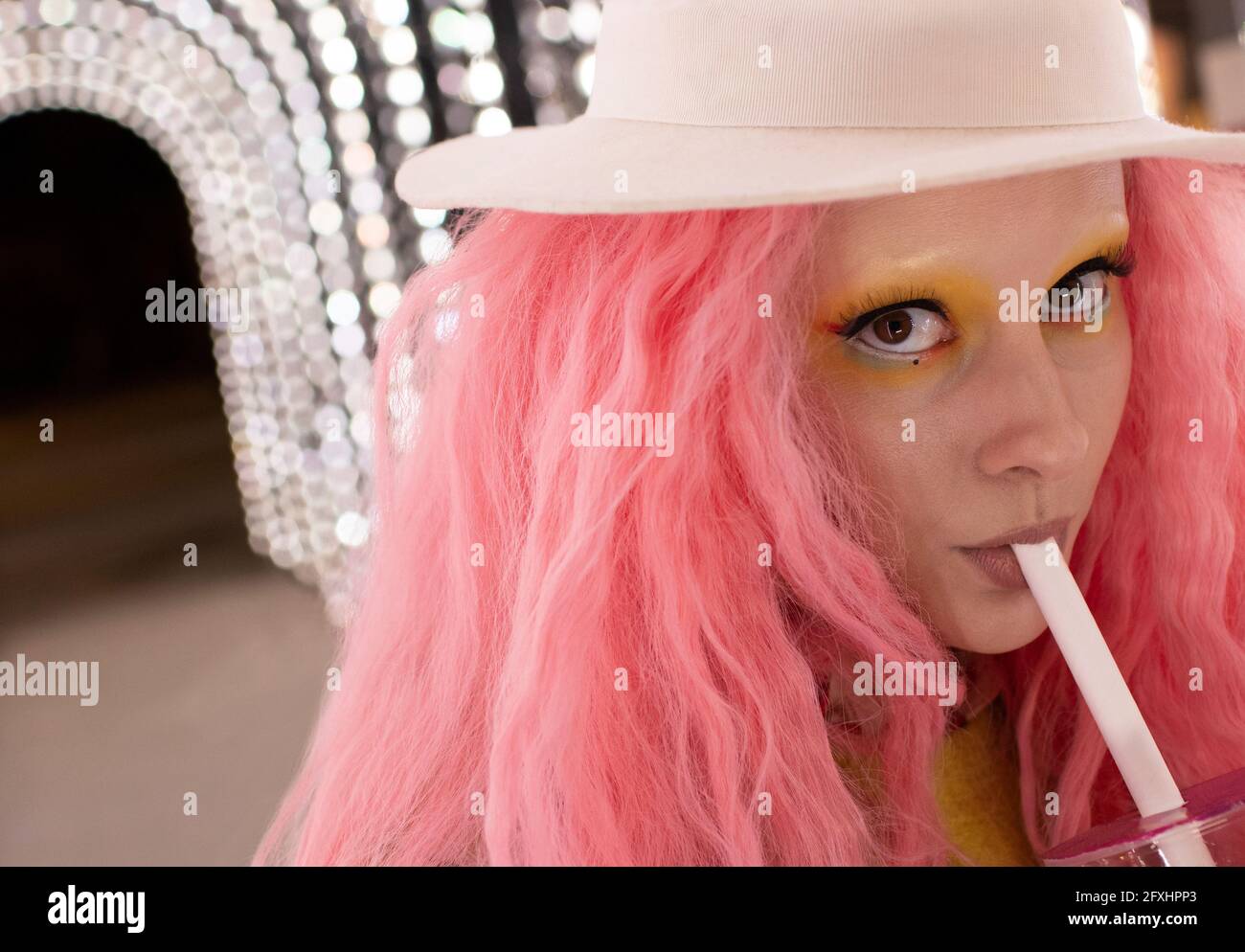 Nahaufnahme Porträt stilvolle Frau mit rosa Haaren, die aus Stroh trinkt Stockfoto