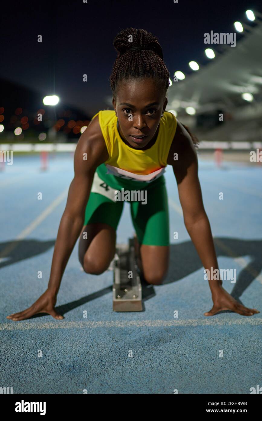 Auf das Porträt fokussierte weibliche Leichtathletik-Athletin am Startblock Stockfoto