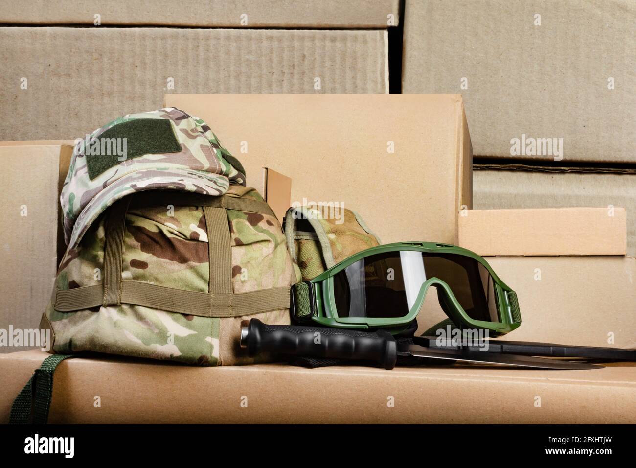 Foto von verschiedenen militärischen getarnten gepanzerten Helm, Mütze und Soldaten-Goodgles.. Verlegung auf gestapelten Kartons. Stockfoto