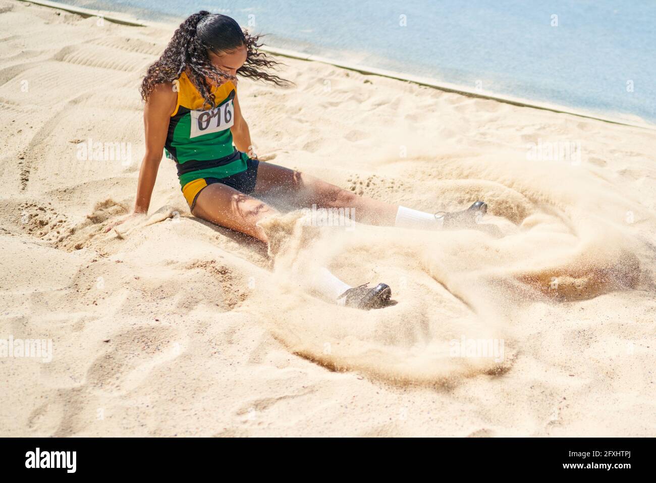 Leichtathletik-Sportlerin, die lange in den Sand springt Stockfoto