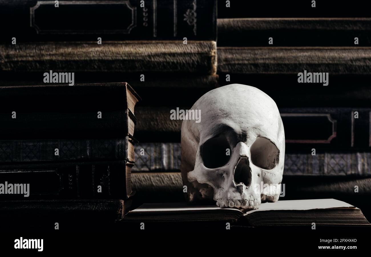 Horror-Foto von Hexerei menschlichen Schädel auf alten Büchern und gestapelten Büchern Hintergrund. Stockfoto