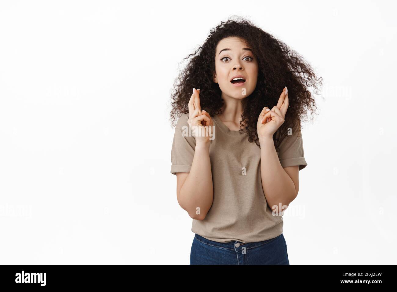 Hoffnungsvolle junge Frau, die nersouly auf Ergebnisse wartet, den Atem anhält und mit gekreuzten Fingern vorwegnimmt, Wünsche macht, um einen Traum betet, der wahr wird Stockfoto