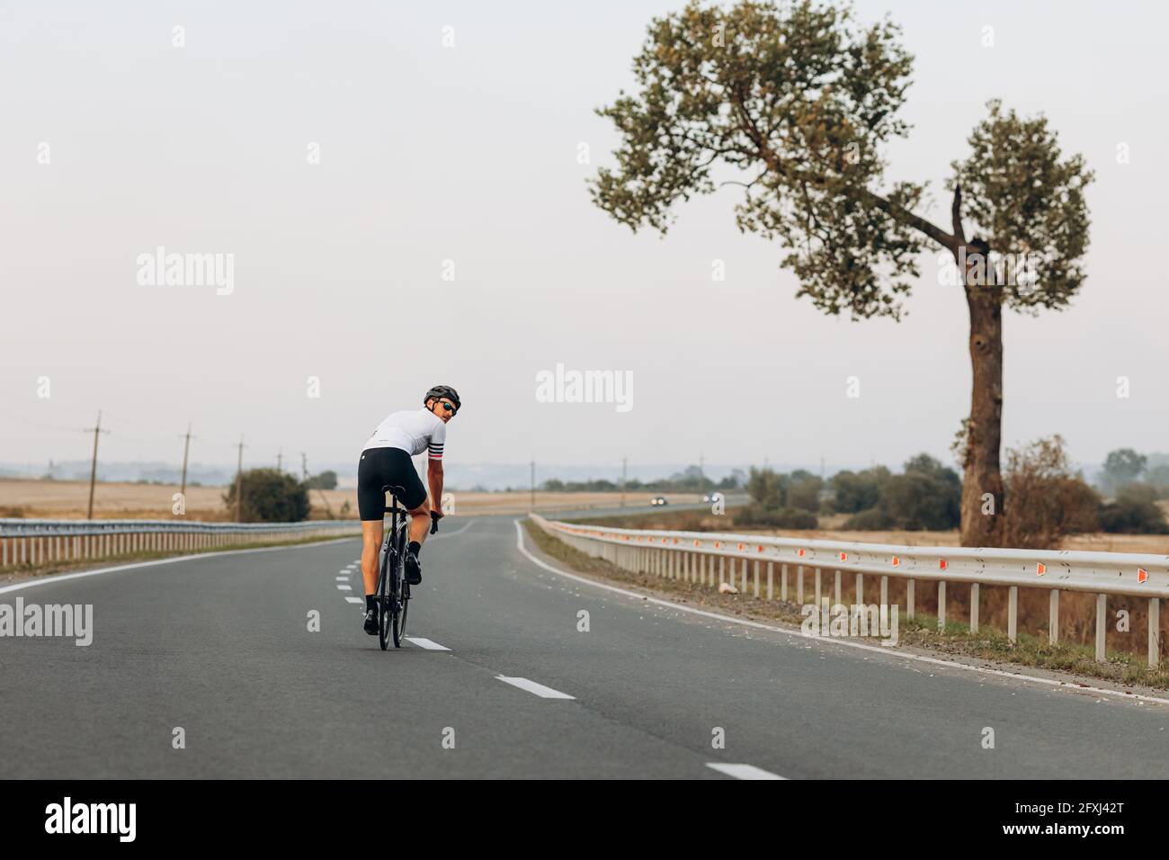 Sportler im Helm üben im Radfahren auf der Straße Stockfoto