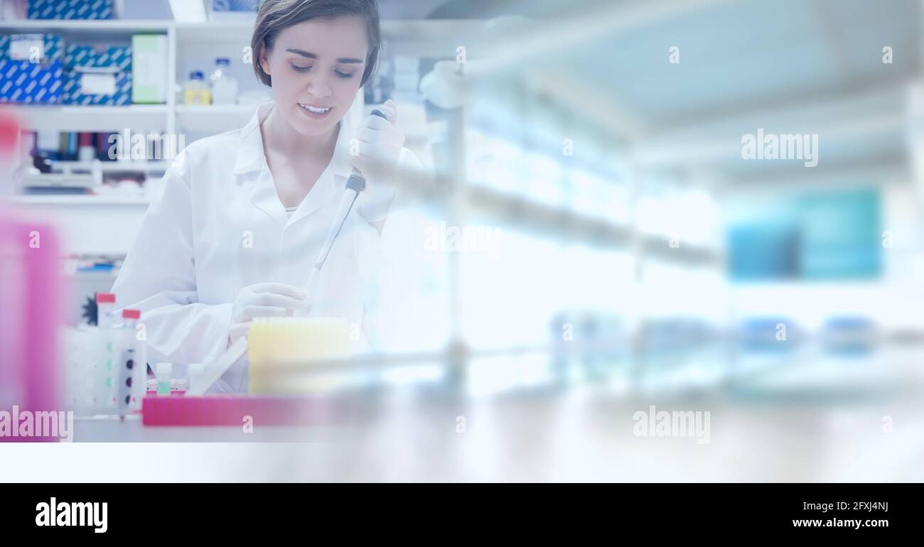 Komposition einer lächelnden Laborantin bei der Arbeit, mit verwischter gelber Kopiefläche rechts Stockfoto