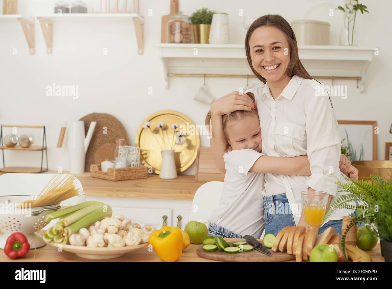 Gesunde Ernährung zu Hause. Eine fröhliche Mutter lacht, hat Spaß und umarmt ihre Tochter. Stockfoto