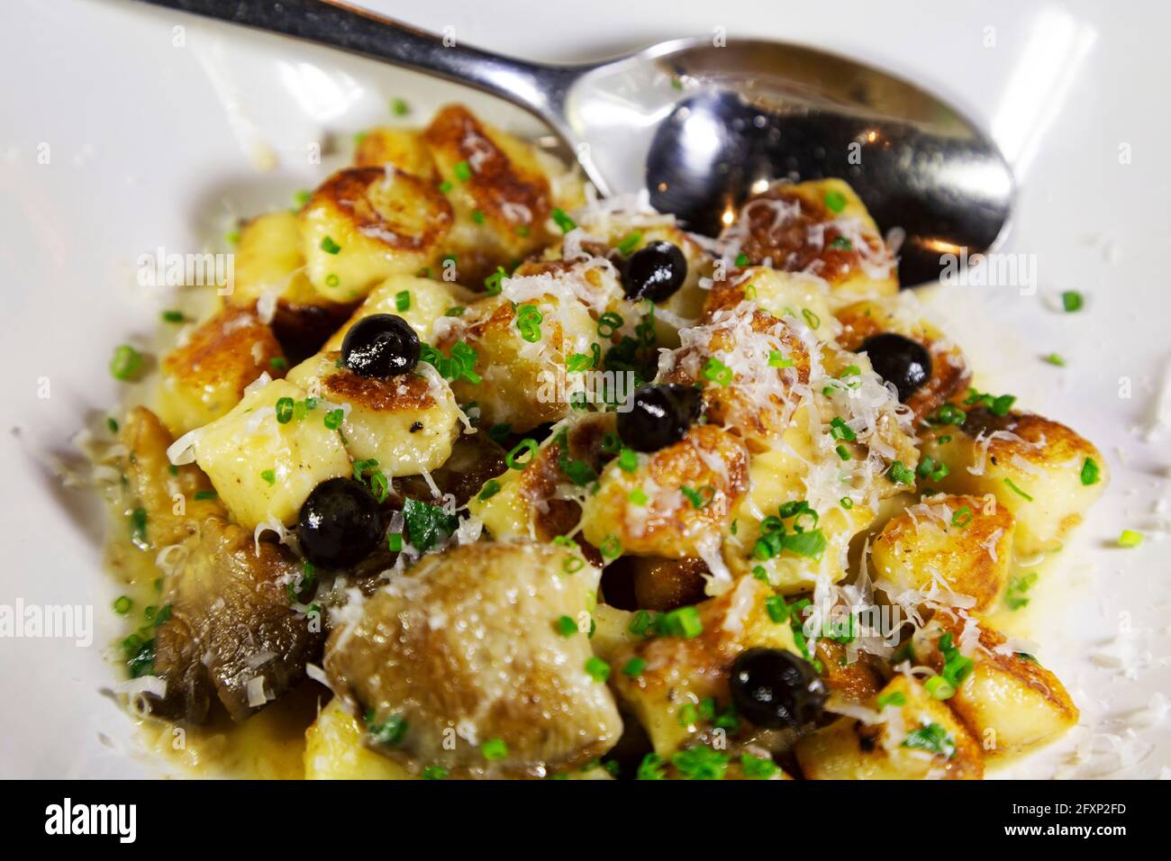 Gnocchi mit Oliven und geriebenem Parmesan gekocht. Das Gericht wird mit Olivenöl beträufelt. Stockfoto