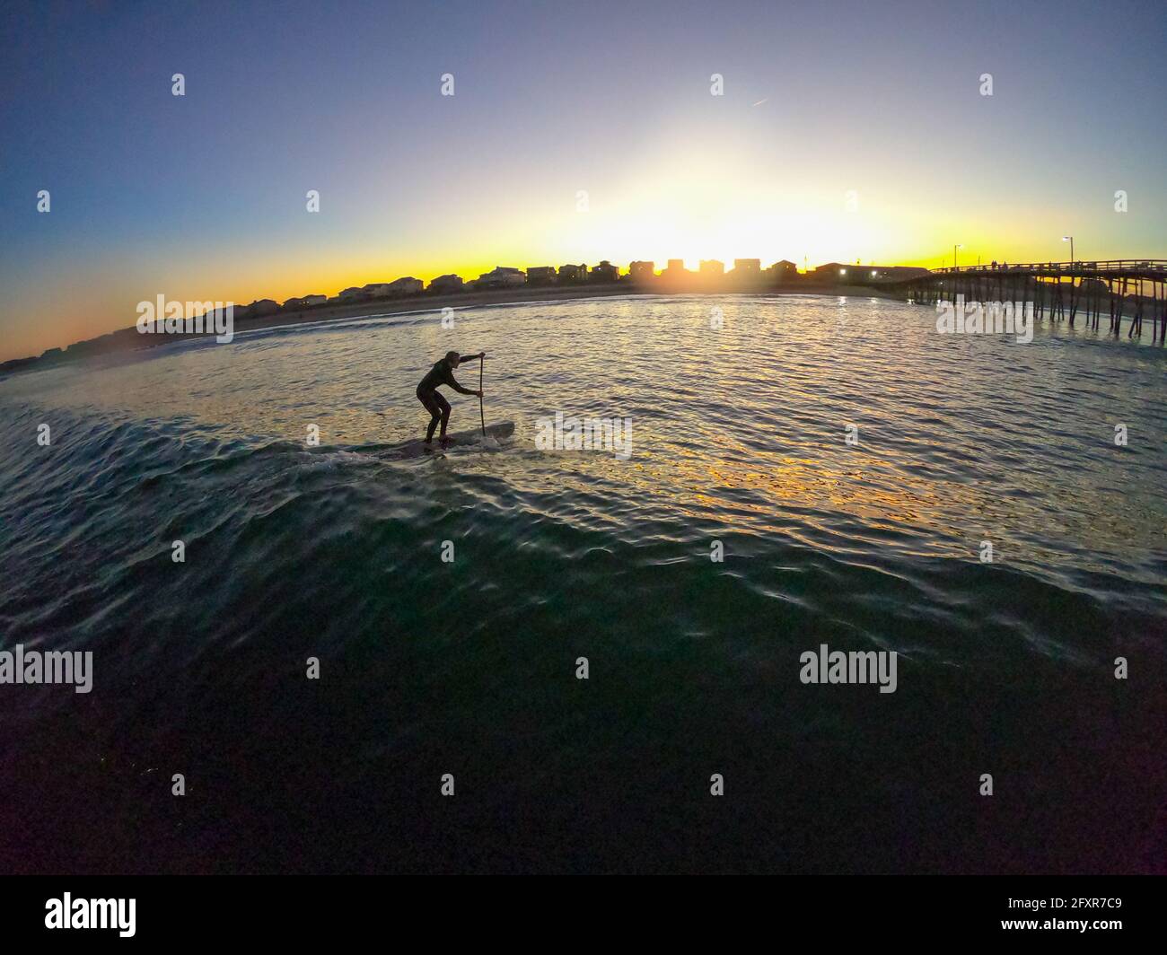 Stand Up Paddle Boarder fängt eine Welle bei Sonnenuntergang, Nags Head, North Carolina, Vereinigte Staaten von Amerika, Nordamerika Stockfoto