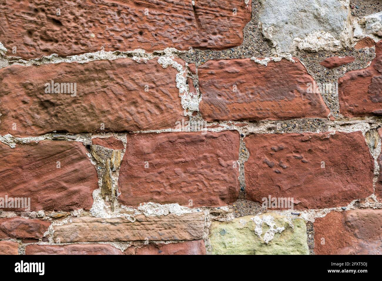 Verwitterter roter Stein mit Gipsresten in der Wand des Lanercost Priory, Cumbria, England, Großbritannien Stockfoto