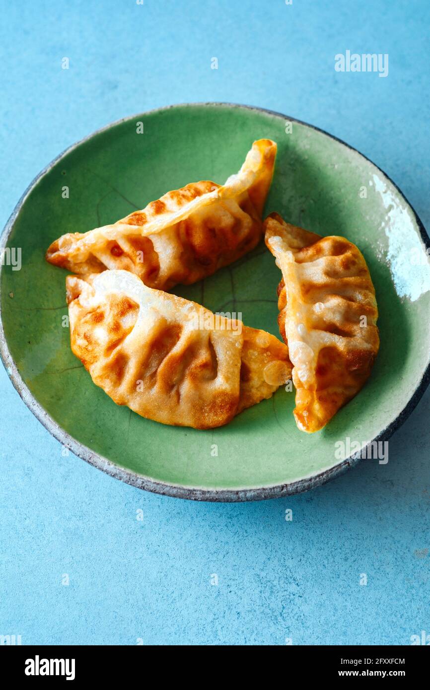 Handgemachte asiatische Knödel auf grünem Teller Stockfoto