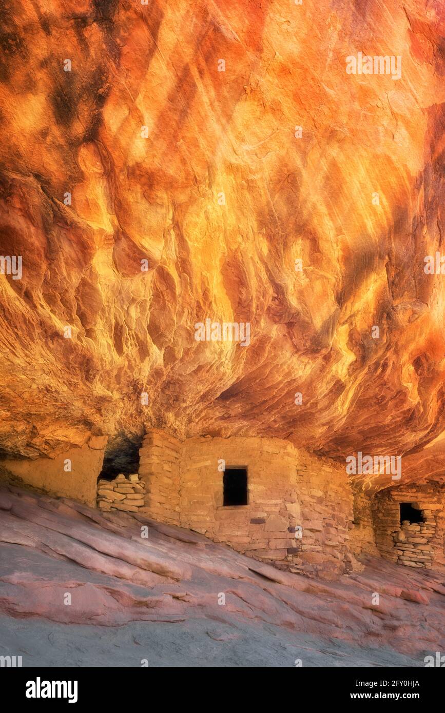 Reflektierendes Sonnenlicht beleuchtet den Sandsteinfelsen oberhalb dieses alten Anasazi Granary und treffend benannt Haus auf Feuerruine in Besuchen Sie Cedar Mesa Pl Stockfoto