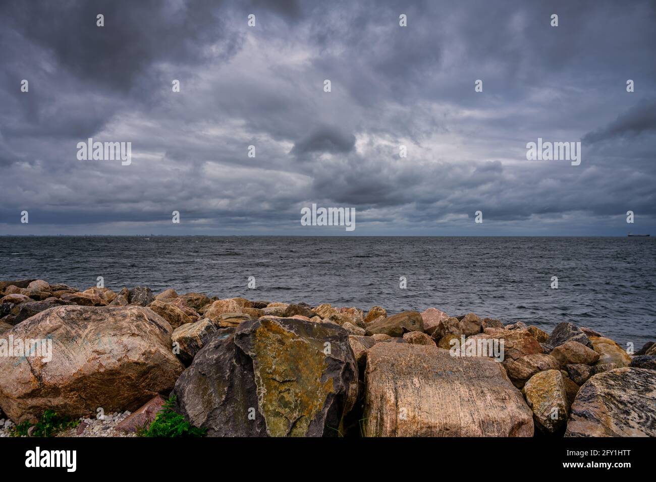 Ein wunderschöner, dramatischer Himmel über dem Meer. Steine in einem Wellenbrecher im Vordergrund. Bild aus Malmö, Schweden Stockfoto