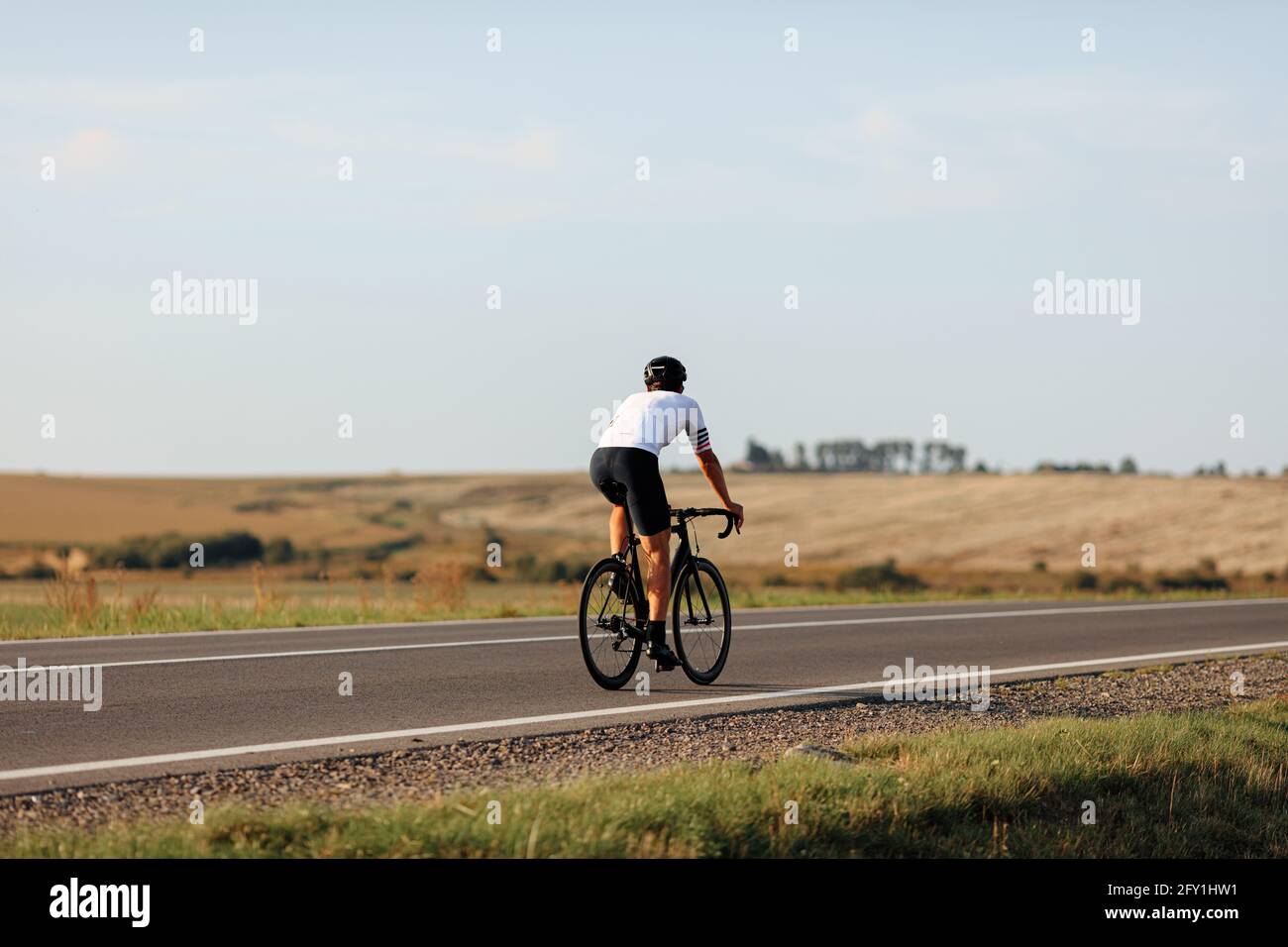 Rückansicht eines jungen Mannes im Helm, der Fahrrad fährt Straße Stockfoto