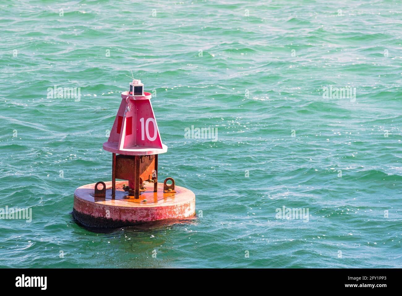 Nahaufnahme einer roten Markierungsboje entlang einer navigierbaren Kanal zu einem Hafen an einem sonnigen Herbsttag Stockfoto