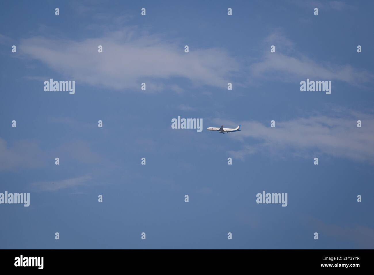 Propellerflugzeug von der Sonne gegen einen blauen Himmel beleuchtet Mit weißen Wolken und Baum - in Bewegung Stockfoto