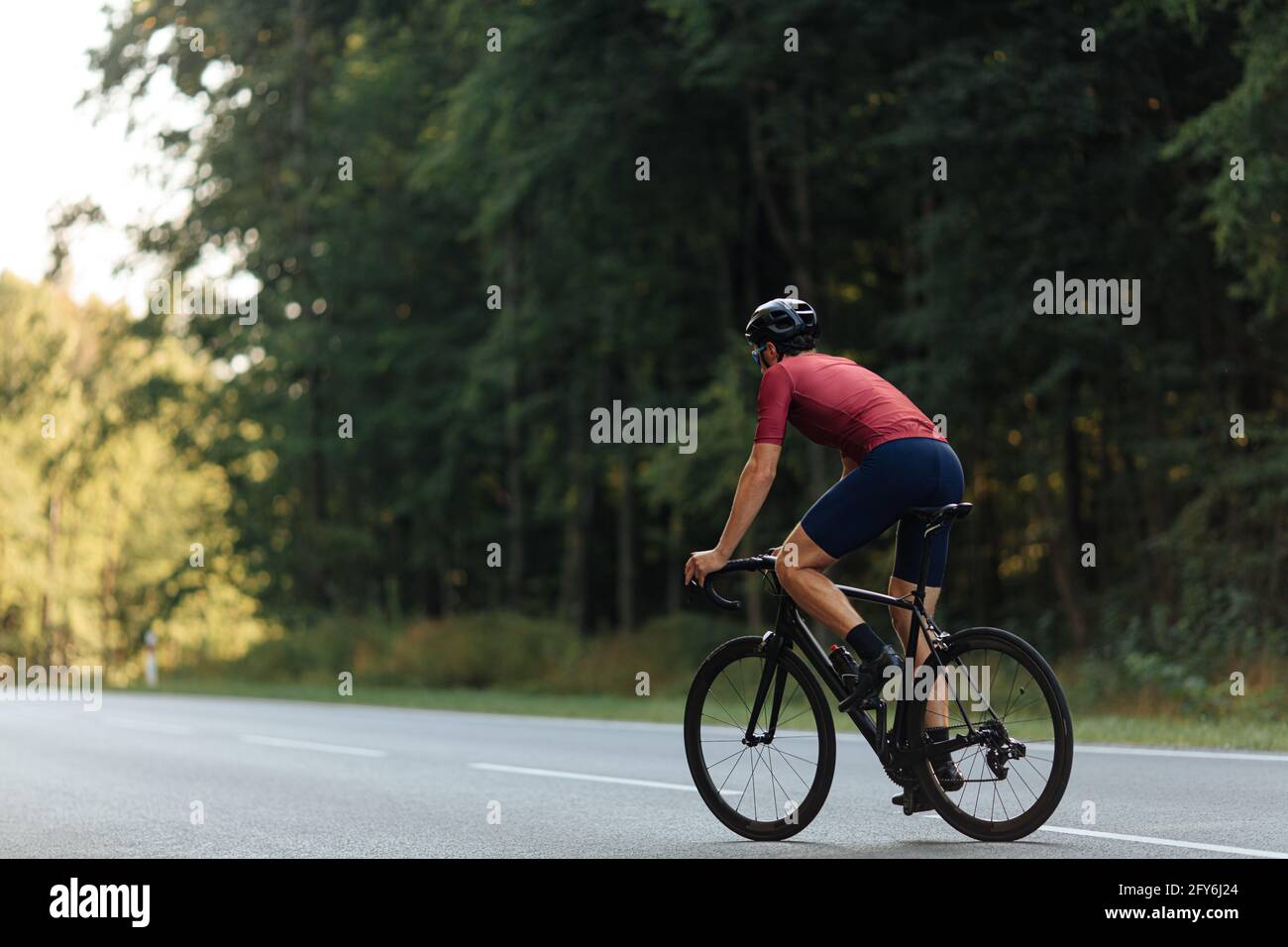 Rückansicht von muskulösen Kerl im Helm Reiten Fahrrad auf Straße Stockfoto