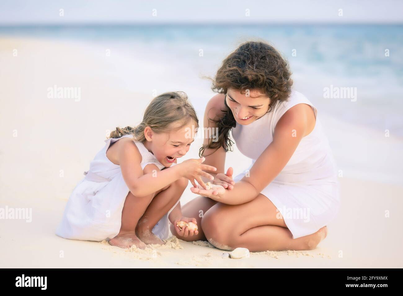 Mutter mit kleiner Tochter, die am Meeresstrand auf den Malediven spielt. Familie am Strand Konzept. Stockfoto